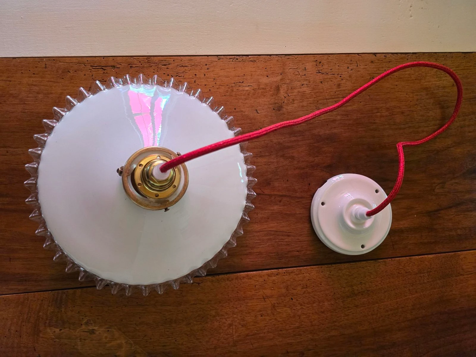 Lámpara de techo con disco opalino blanco y bordes transparentes sobre cable rojo y plafón de porcelana – photo 3